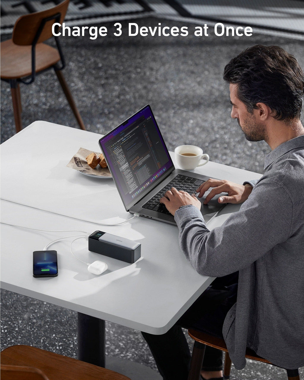 Anker 737 power bank charging a laptop, phone, and earbuds on a table.