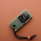 Apple Watch Ultra in an olive green miniPhone Ultra case with a black cord on an orange background.